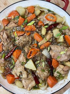 a pot filled with meat and vegetables on top of a wooden table