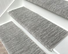 three gray rugs sitting on top of a white floor