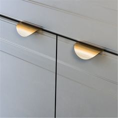 two brass handles on the drawers of a gray cabinet with white painted woodgrain