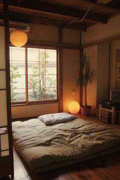 a bed sitting in the middle of a room next to a window with lights on it