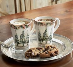 two coffee mugs with cookies on a silver tray