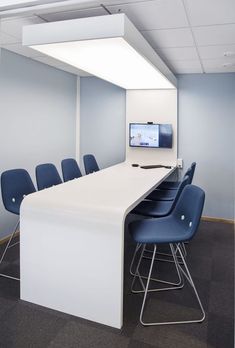 an empty conference room with blue chairs and a flat screen tv mounted on the wall