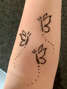 two butterflies are drawn on the side of a woman's arm with black ink