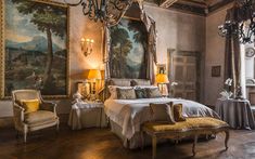 a large bed sitting in a bedroom next to a painting on the wall and chandelier