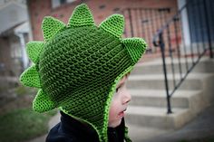 a little boy wearing a green knitted dinosaur hat