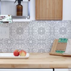 two apples sitting on a plate in the middle of a kitchen counter with a cutting board