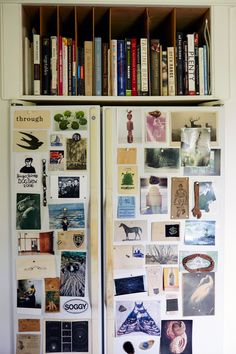 a refrigerator covered in pictures and magnets next to a book shelf filled with books