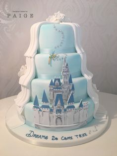 a three tiered cake is decorated with blue frosting and white icing castle