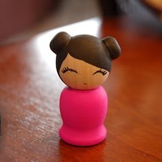 a small toy doll sitting on top of a wooden table