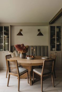 a dining room table with chairs and a vase filled with flowers on top of it