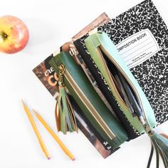 an apple and some scissors on a table with notebooks, pencils and papers