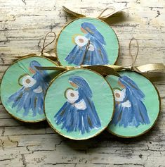 four blue birds painted on green plates with gold trim around the edges and hanging from a golden ribbon