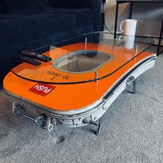 an orange table with a remote control on it and a black couch in the background