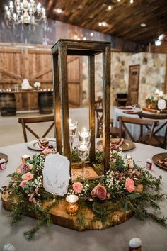 the centerpiece is made out of wood and surrounded by greenery, candles, and flowers