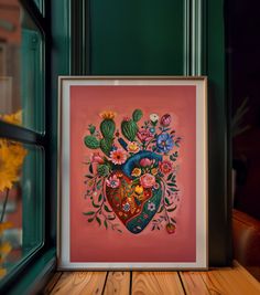 a heart shaped painting on a pink background with flowers and cacti in it