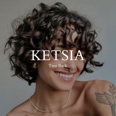 a woman with curly hair and piercings smiles at the camera while wearing a necklace that reads ketsia tree bark