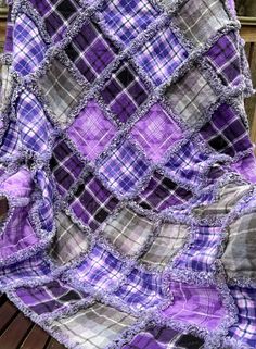 a purple and grey blanket sitting on top of a wooden bench