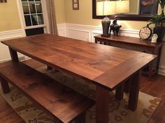 a dining room table with benches in front of it and a clock on the wall