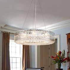 a chandelier hanging from the ceiling in a living room next to a window