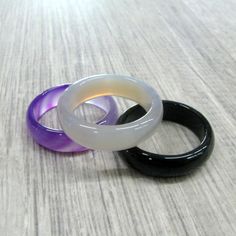 three different colored rings sitting next to each other on a wooden table with white and black bands