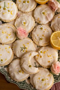 lemon cookies with white frosting and pink flowers on a green plate next to a flowered napkin