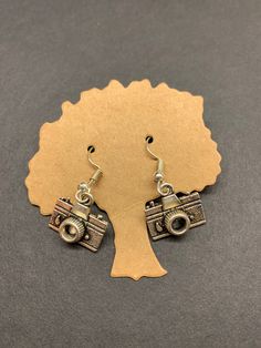 a pair of earrings with an old camera on it