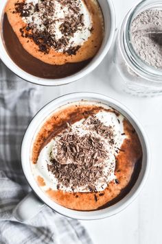 two white bowls filled with desserts on top of a table