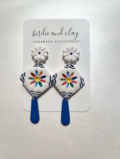 two white and blue earrings with flowers on them