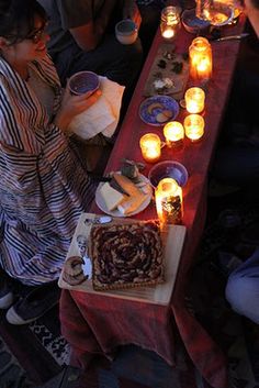 people sitting around a long table with candles on it