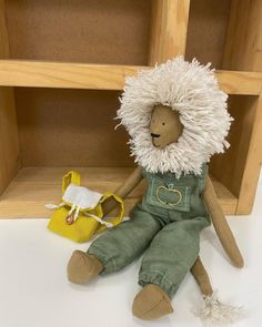 a stuffed animal sitting on top of a white floor next to a yellow purse and wooden shelves