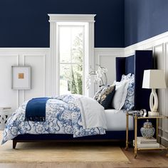 a bedroom with blue walls and white bedding in the center, along with two side tables