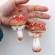 two small mushrooms are being held in the palm of someone's hand while wearing gold ear wires