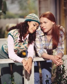 two young women leaning on a wooden bench and looking at each other's eyes