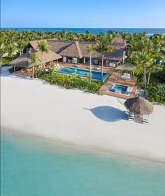 an aerial view of a beach house with a pool and palm trees in the foreground