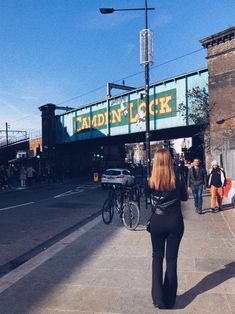 a woman walking down the street in front of a bridge