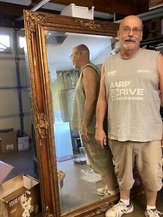 an older man standing in front of a mirror with his hands on his hips and looking at the camera