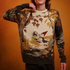 a young man is posing for the camera wearing a sweater with cartoon characters on it