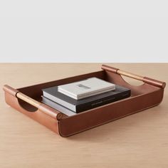 a desk with a pen, notebooks and books in a leather case on it