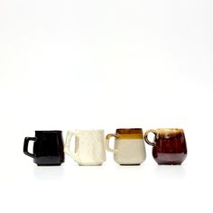 three different colored mugs sitting next to each other on a white surface with no one around them