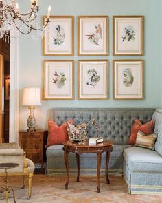 a living room filled with furniture and framed pictures on the wall above a coffee table