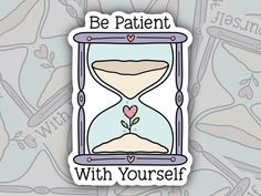 an hourglass sticker with the words be patient with yourself on it and hearts in the sand