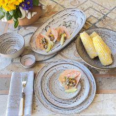 three plates with food on them sitting on a table next to silverware and utensils