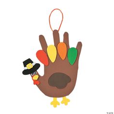 a hand with a turkey wearing a top hat and holding a thanksgiving ornament