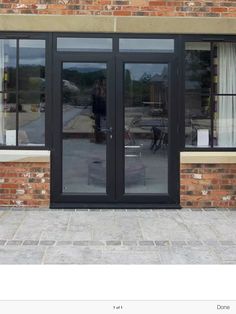 a brick building with two large black doors and some potted plants on the outside