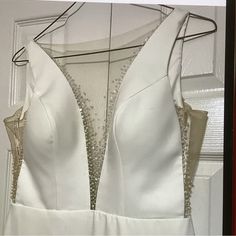 the back of a white dress hanging on a hanger