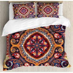 a bed covered in a colorful comforter and pillow case next to a white wall