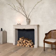 a room with a fireplace, chair and vase on top of the mantel in front of it