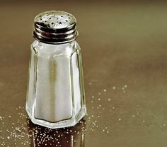 a salt and pepper shaker sitting on top of a black surface with silver flecks