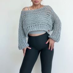 a woman wearing black leggings and a cropped top is posing in front of a white wall