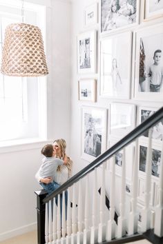 two people kissing on the stairs in front of pictures hanging on the wall above them